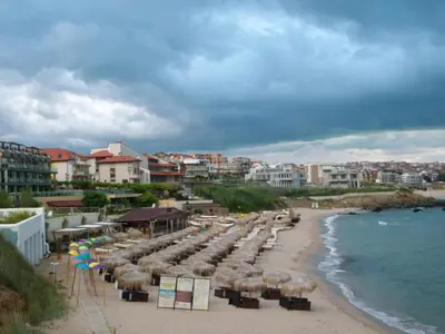 a beach with umbrellas and chairs and the ocean at Barex Family Hotel in Sozopol