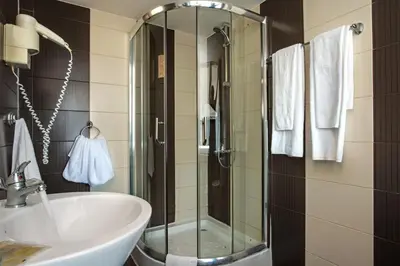 a bathroom with a glass shower and a sink at Flagman Hotel in Sozopol