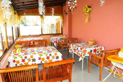 a dining room with two tables and wooden chairs at Hotel Apolis in Sozopol