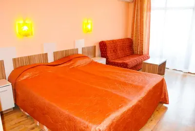 a hotel room with a bed and a chair at Hotel Apolis in Sozopol