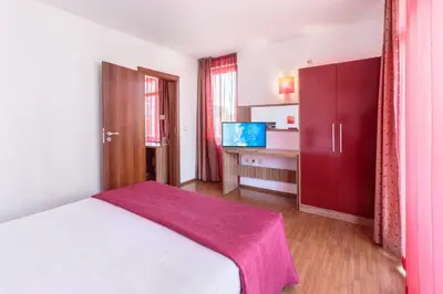 a bedroom with a bed and a desk and a kitchen at Hotel Apolis in Sozopol