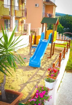 a playground with a blue slide and some flowers at Hotel Apolis in Sozopol