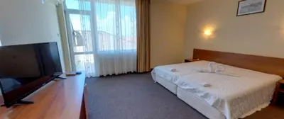 a bedroom with a bed and a flat screen tv at Sandor Hotel in Nesebar