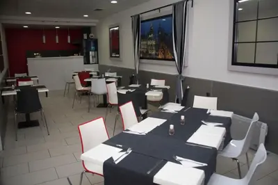 a dining room with tables and white chairs and a unintention at Gran Via in Burgas City