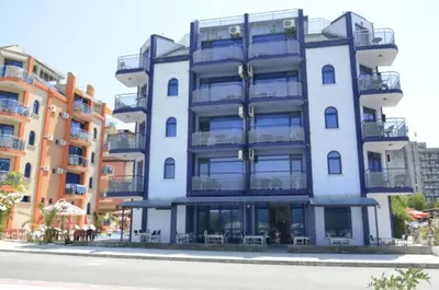 a tall white building with tables and chairs in front of it at Хотел Калипсо Блу in Primorsko