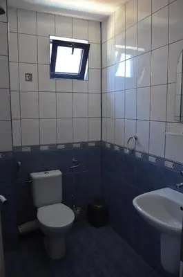a bathroom with a toilet and a sink and a window at Хотел Калипсо Блу in Primorsko