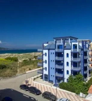 a large apartment building with cars parked in front of it at Хотел Калипсо Блу in Primorsko