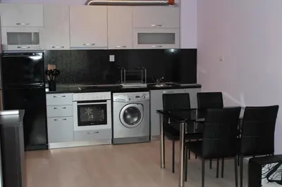 a kitchen with a washing machine and a table with chairs at Paradise Day in Pomorie