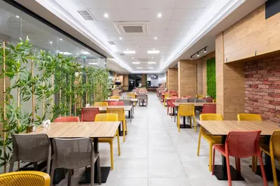 a restaurant with tables and chairs and plants at Avenue Hotel in Burgas City