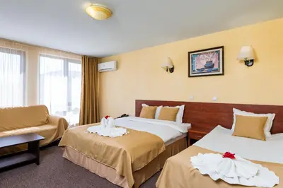 a hotel room with two beds and a chair at Avenue Hotel in Burgas City