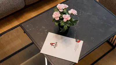 a table with a vase with pink flowers on it at Avenue Hotel in Burgas City