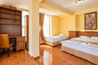 a hotel room with two beds and a desk at Avenue Hotel in Burgas City