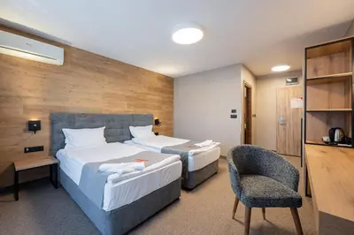 a hotel room with two beds and a chair at Avenue Hotel in Burgas City