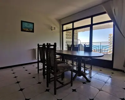 a dining room with a table and chairs and a window at Lazur SeaView Apartment in Pomorie