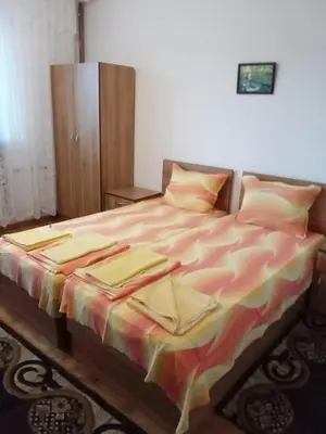 a bedroom with a bed with a colorful blanket on it at Стаи за гости Петрови in Primorsko
