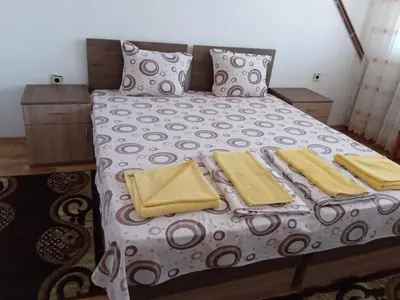 a bed with yellow blankets and pillows on it at Стаи за гости Петрови in Primorsko
