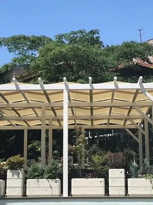 a wooden pergola in a garden with trees in the background at Family Hotel Belle Epoque Beach in Varna City