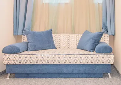 a couch with blue pillows sitting in a room at Family Hotel Belle Epoque Beach in Varna City