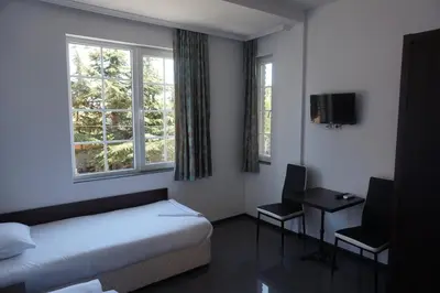 a bedroom with a bed and a desk and two windows at SeaSide Guest Rooms in Burgas City