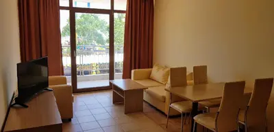 a living room with a couch and a table and a television at Kaya Apartments in Sunny Beach