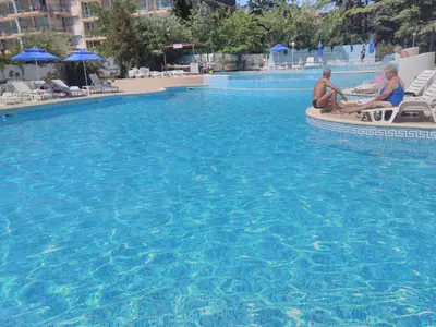 two people sitting on chairs in a swimming pool at Hotel Yantra in Sunny Beach