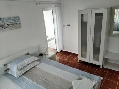 a white bedroom with a bed and a window at Guesthouse Kolevi in Lozenets