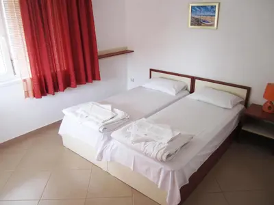 a bedroom with a bed with white sheets and a red curtain at Guesthouse Kolevi in Lozenets