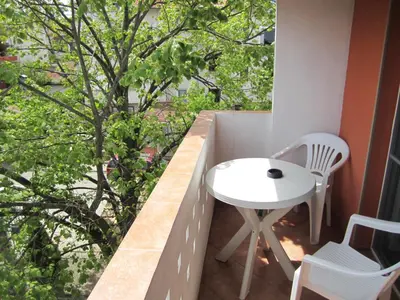 a small white table and chairs on a balcony with a tree at Guesthouse Kolevi in Lozenets