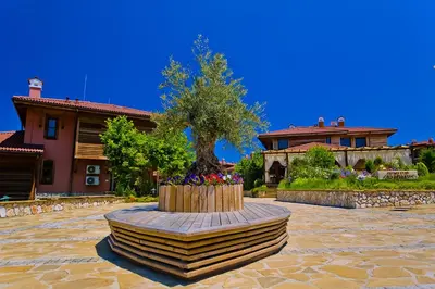 a tree in a flower bed in front of a house at Sozopolis Holiday Village in Sozopol