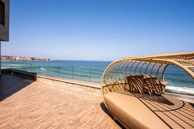 a rattan bench sitting on a balcony overlooking the ocean at Villa Lili in Sozopol