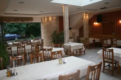 a restaurant with white tables and wooden chairs at Mirana Family Hotel in Burgas City
