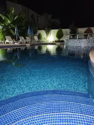 a large swimming pool at night with chairs and umbrellas at Mirana Family Hotel in Burgas City