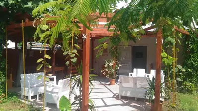 a patio with white chairs and a pergola at Aura in Primorsko
