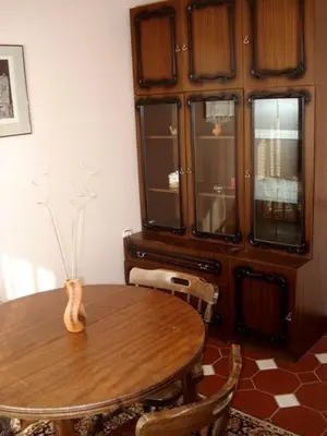 a dining room with a wooden table and some windows at Style Apartment in Pomorie