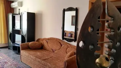 a living room with a brown couch and a mirror at Style Apartment in Pomorie
