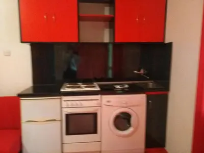 a kitchen with a stove and a sink and red cabinets at Studio Ekzarh in Varna City