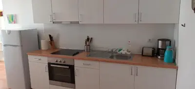 a kitchen with white cabinets and a sink and a refrigerator at Sunny House in Byala