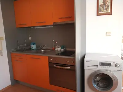a kitchen with orange cabinets and a washing machine at Sunny House in Byala