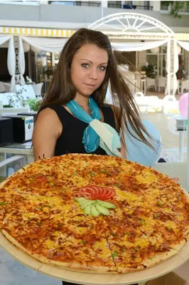 a woman is looking at a large pizza at Karlovo Hotel in Sunny Beach