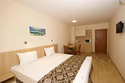 a bedroom with a large bed and a kitchen at Karlovo Hotel in Sunny Beach