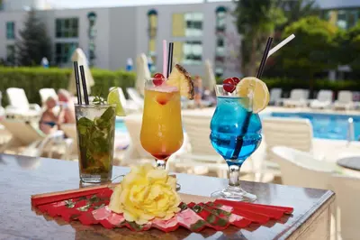 three cocktails sitting on a table near a pool at Karlovo Hotel in Sunny Beach