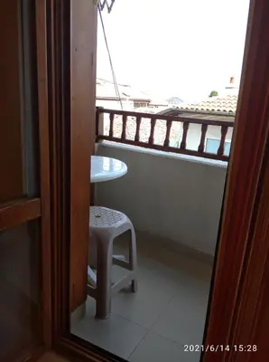 a balcony with a stool and a table and a window at Sozopol House Dimitrovi in Sozopol