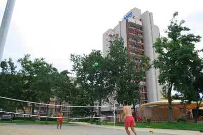 two men playing a game of volleyball in front of a building at Hotel Iskar & Aquapark - All Inclusive in Sunny Beach