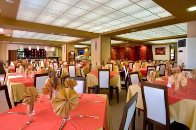 a restaurant with tables and chairs with red and yellow tablecloths at Hotel Iskar & Aquapark - All Inclusive in Sunny Beach