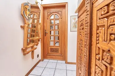 a hallway with a wooden door and a tiled floor at Апартамент Бриз in Burgas City