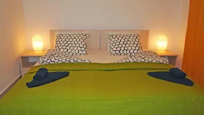 a bedroom with a large green bed with two lamps at Villa Burkopolis in Sozopol