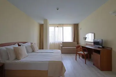 a bedroom with a bed and a desk and a television at Perla Plaza Hotel - All Inclusive in Primorsko