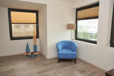 a living room with a blue chair and a window at Hotel Burgas Free University in Burgas City