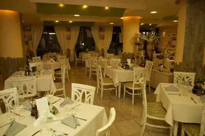 a dining room with white tables and white chairs at Hotel Fors in Burgas City