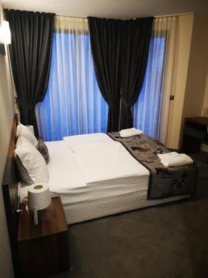 a bedroom with a large bed with blue curtains at Family Hotel Novel City in Burgas City